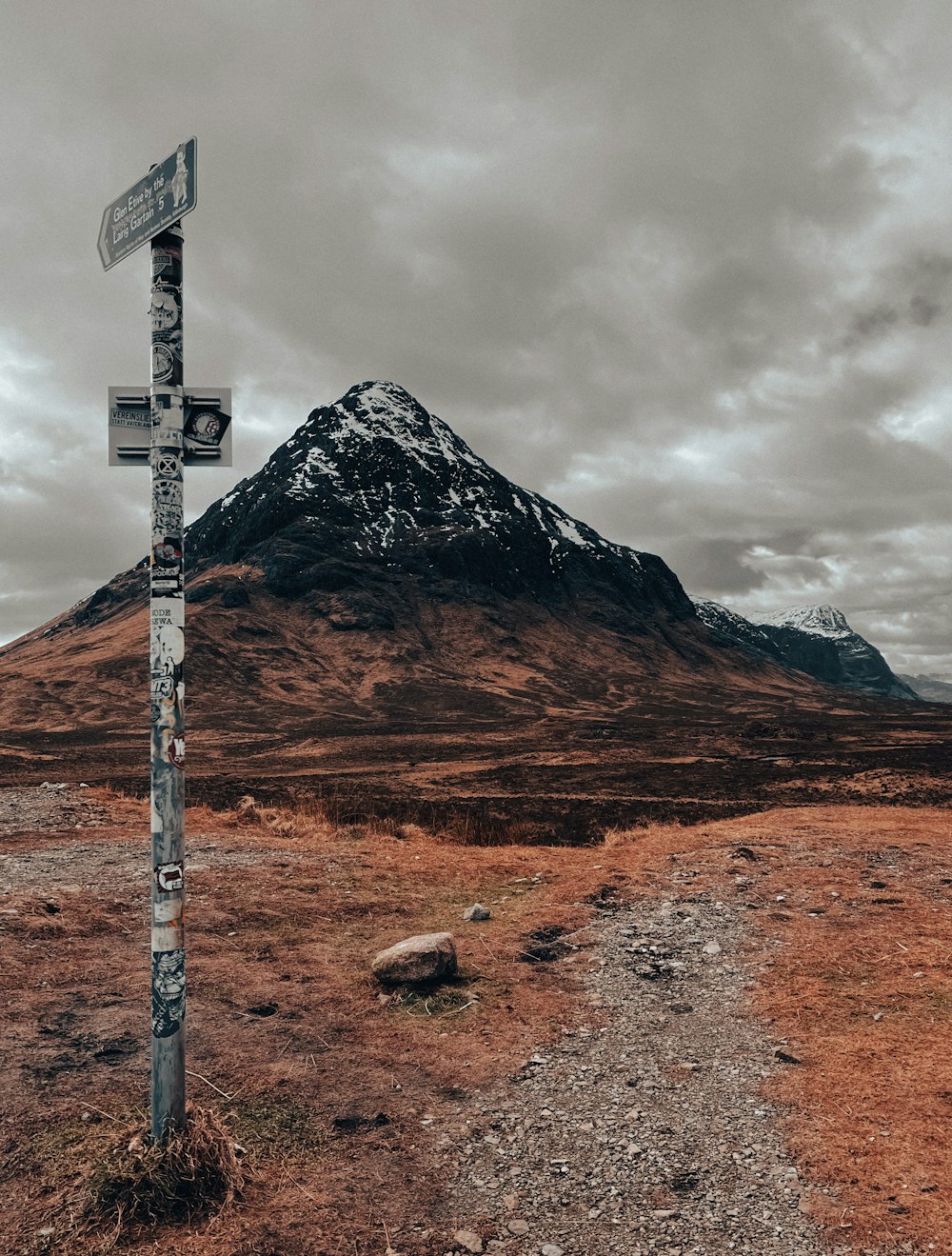 ein Wegweiser auf einem Feld mit einem Berg im Hintergrund