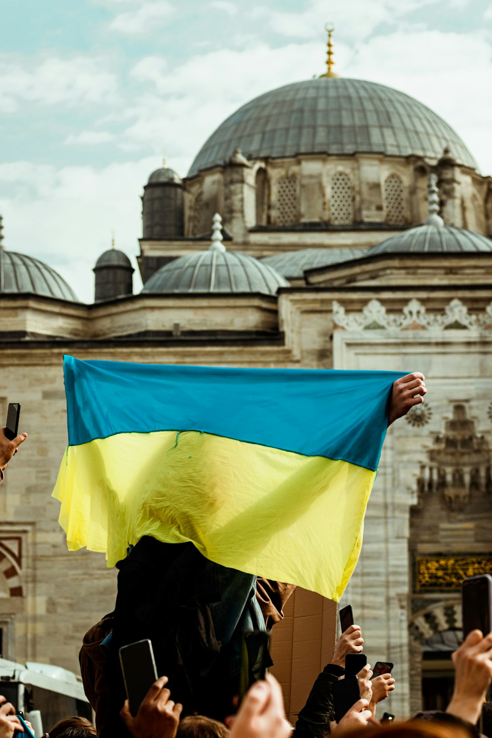 a crowd of people holding up a blue and yellow flag