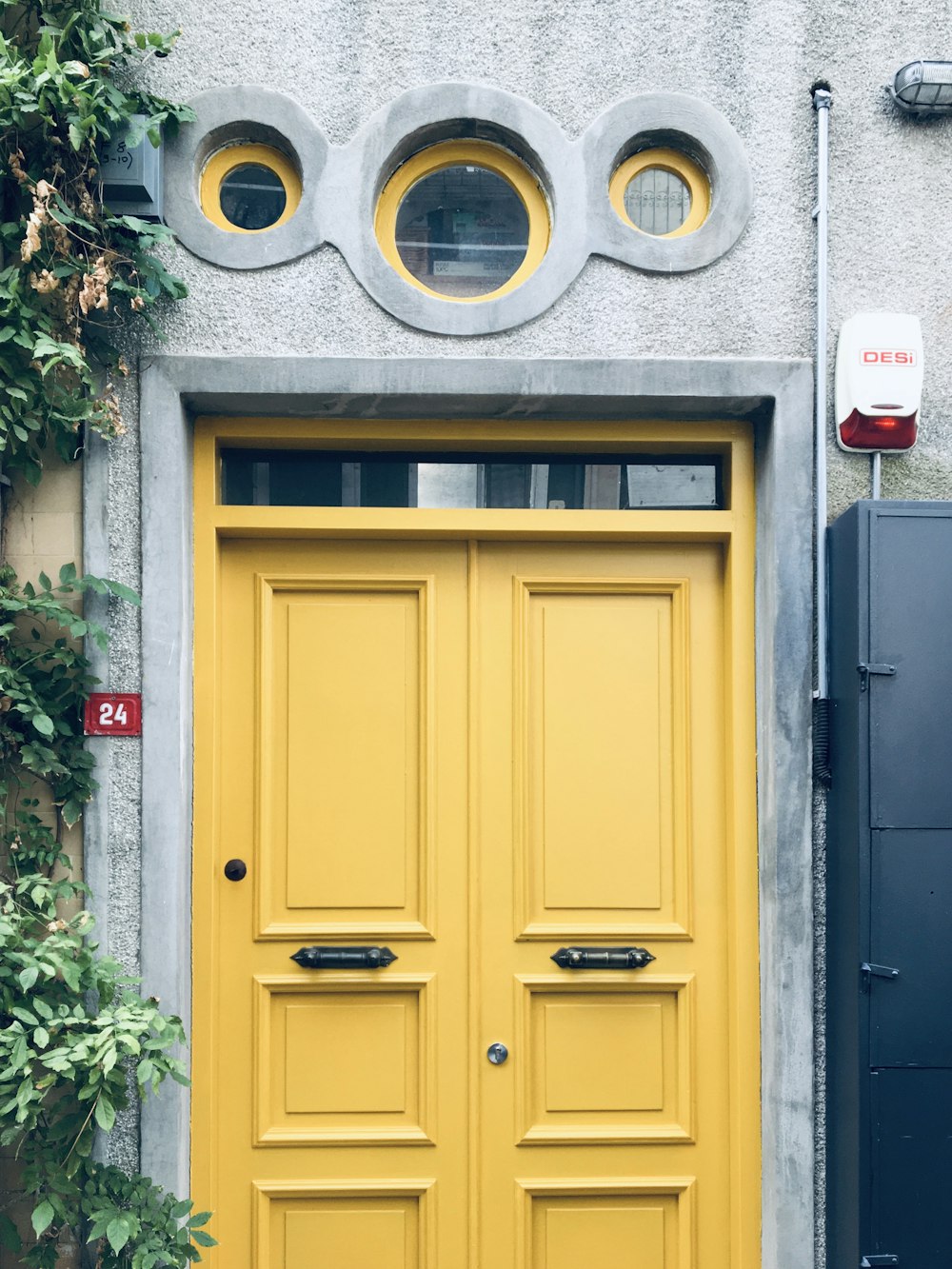 a yellow door with two round windows on a building