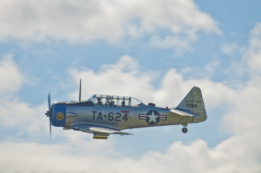 um pequeno avião voando através de um céu azul nublado
