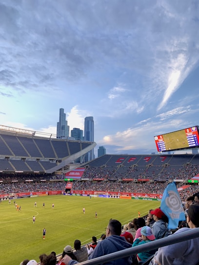 A passionate soccer fan analyzing match stats on a laptop with a football stadium in the background.