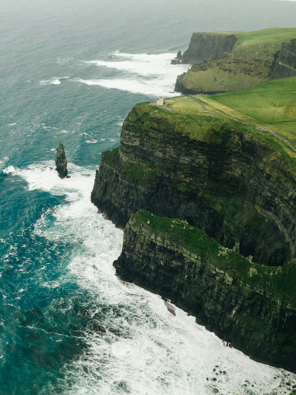 a large body of water next to a lush green hillside