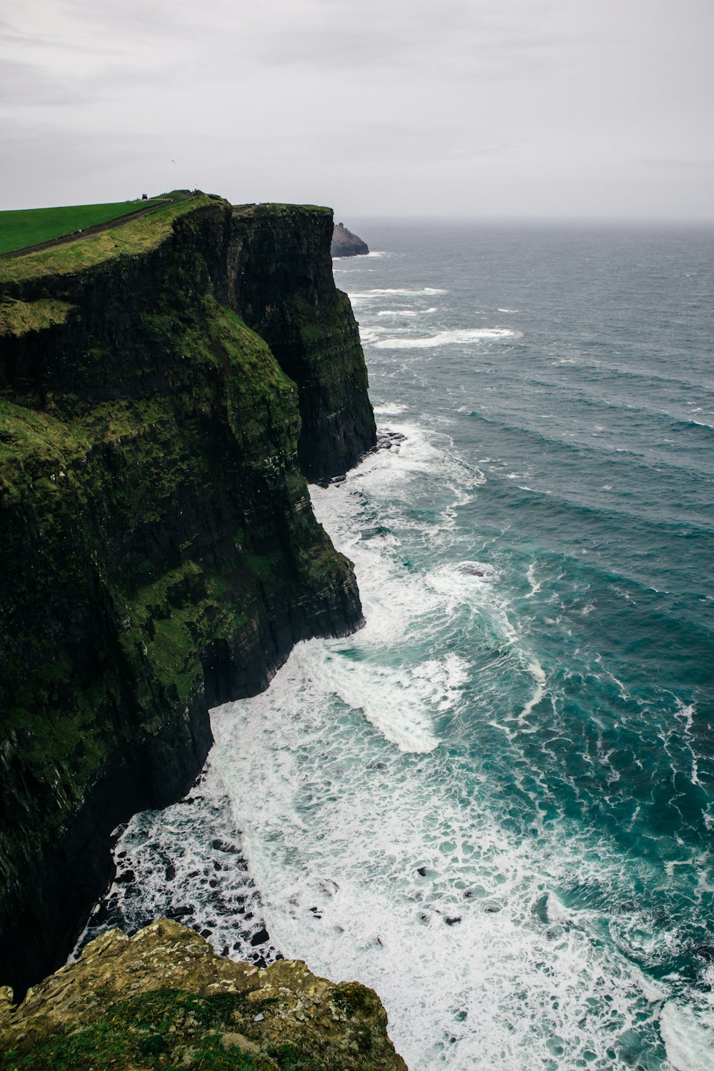 a cliff overlooking the ocean on a cloudy day