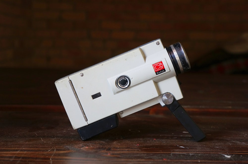 Eine kleine weiße Kamera sitzt auf einem Holztisch