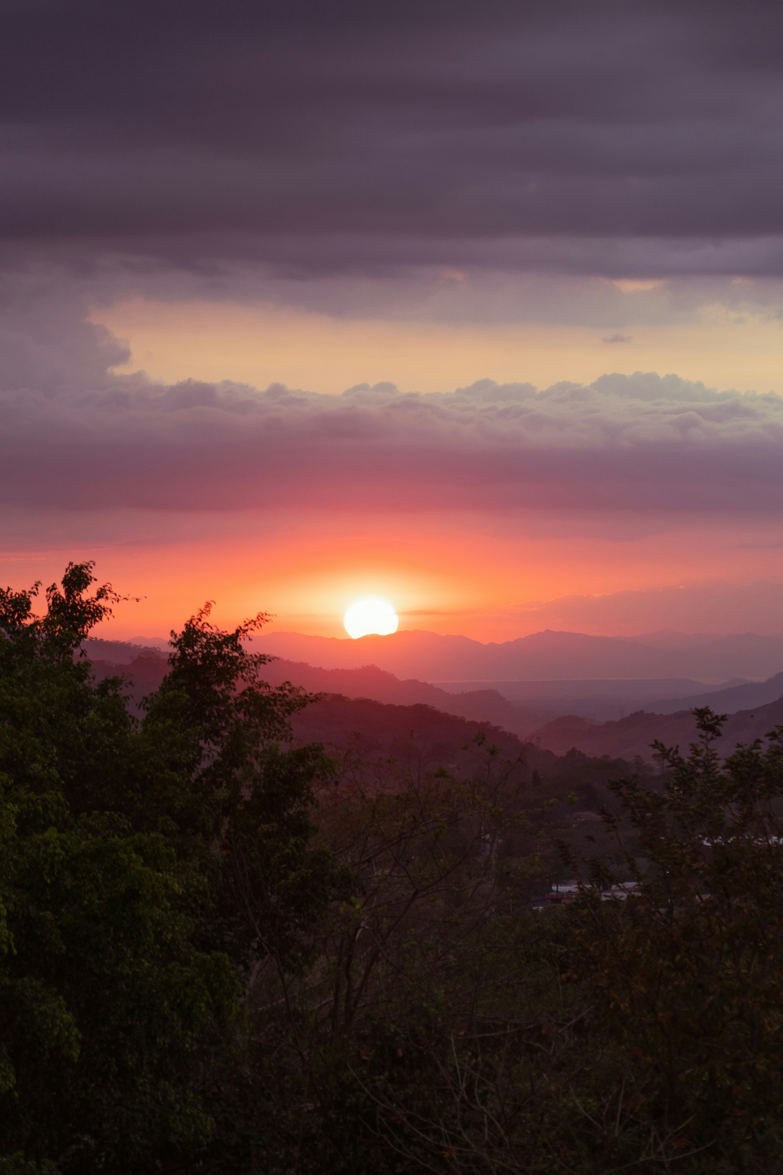 the sun is setting over the mountains in the distance
