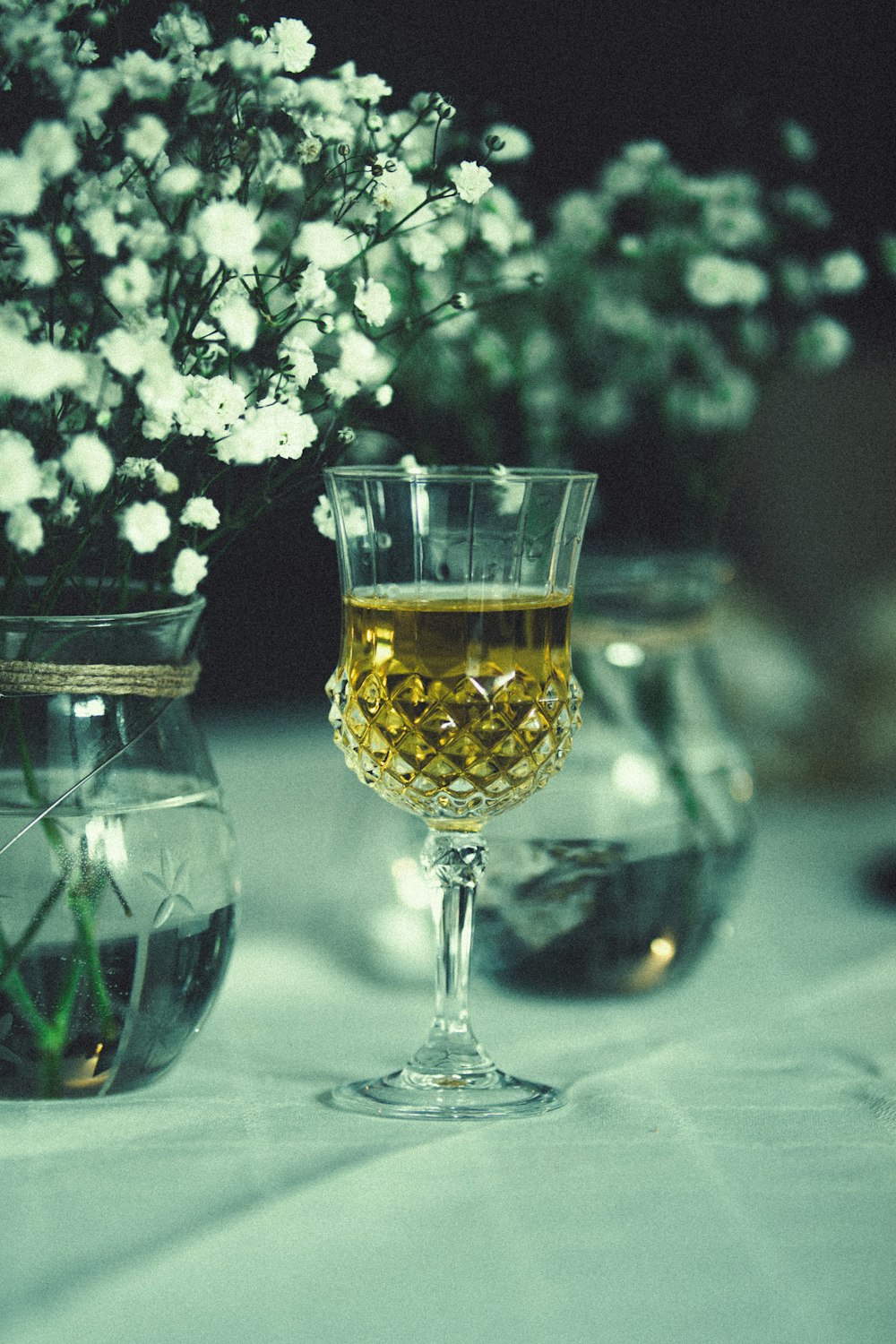 a glass of wine sitting on a table next to a vase of flowers