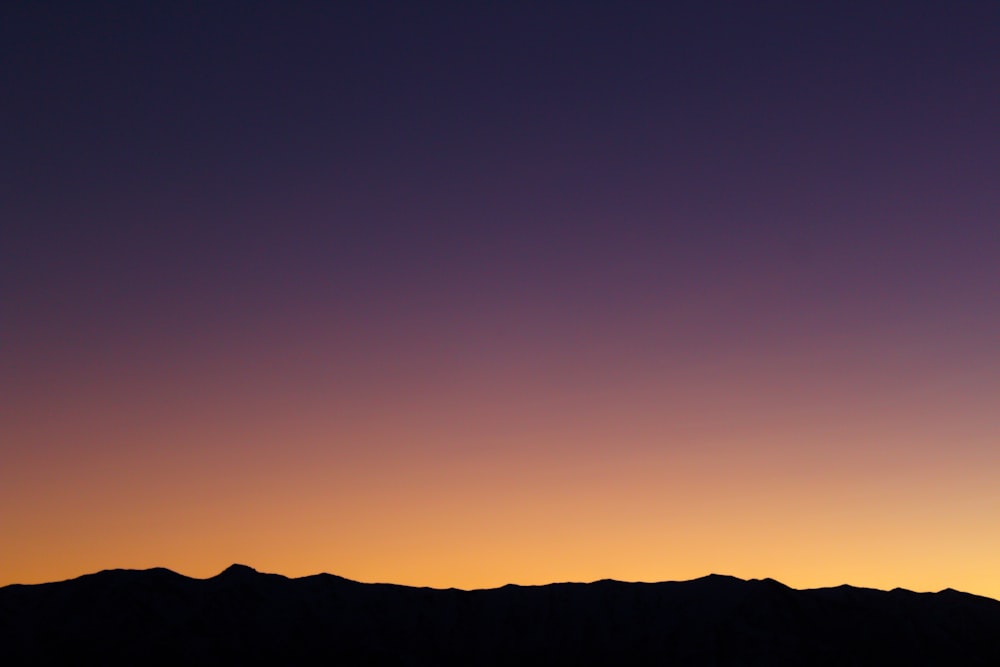 a plane flying over a mountain range at sunset