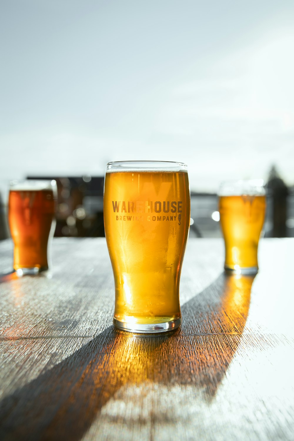 three glasses of beer sitting on top of a wooden table