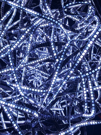 A complex tangle of illuminated LED light strips in various directions, creating a dense and intricate pattern against a dark background.