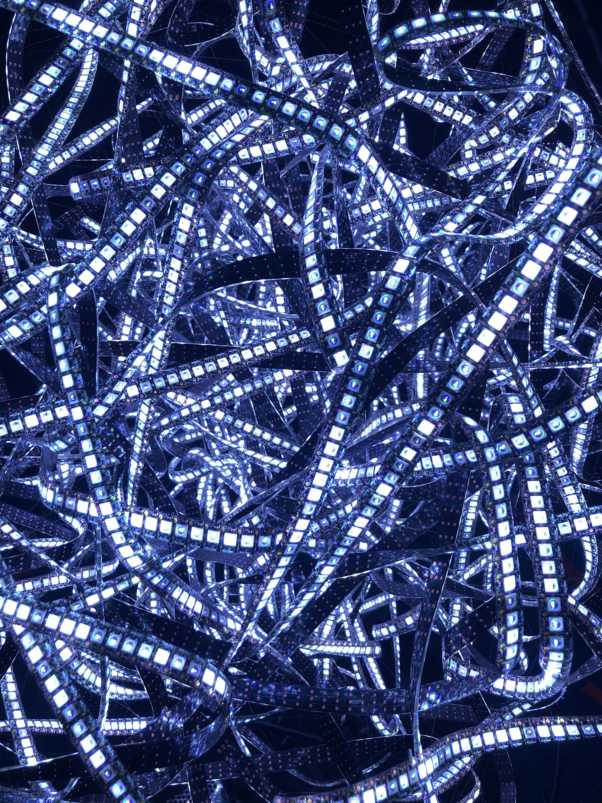 Close-up of multi-colored LED strips weaving through a modern architectural space, highlighting clean lines and dynamic color transitions.