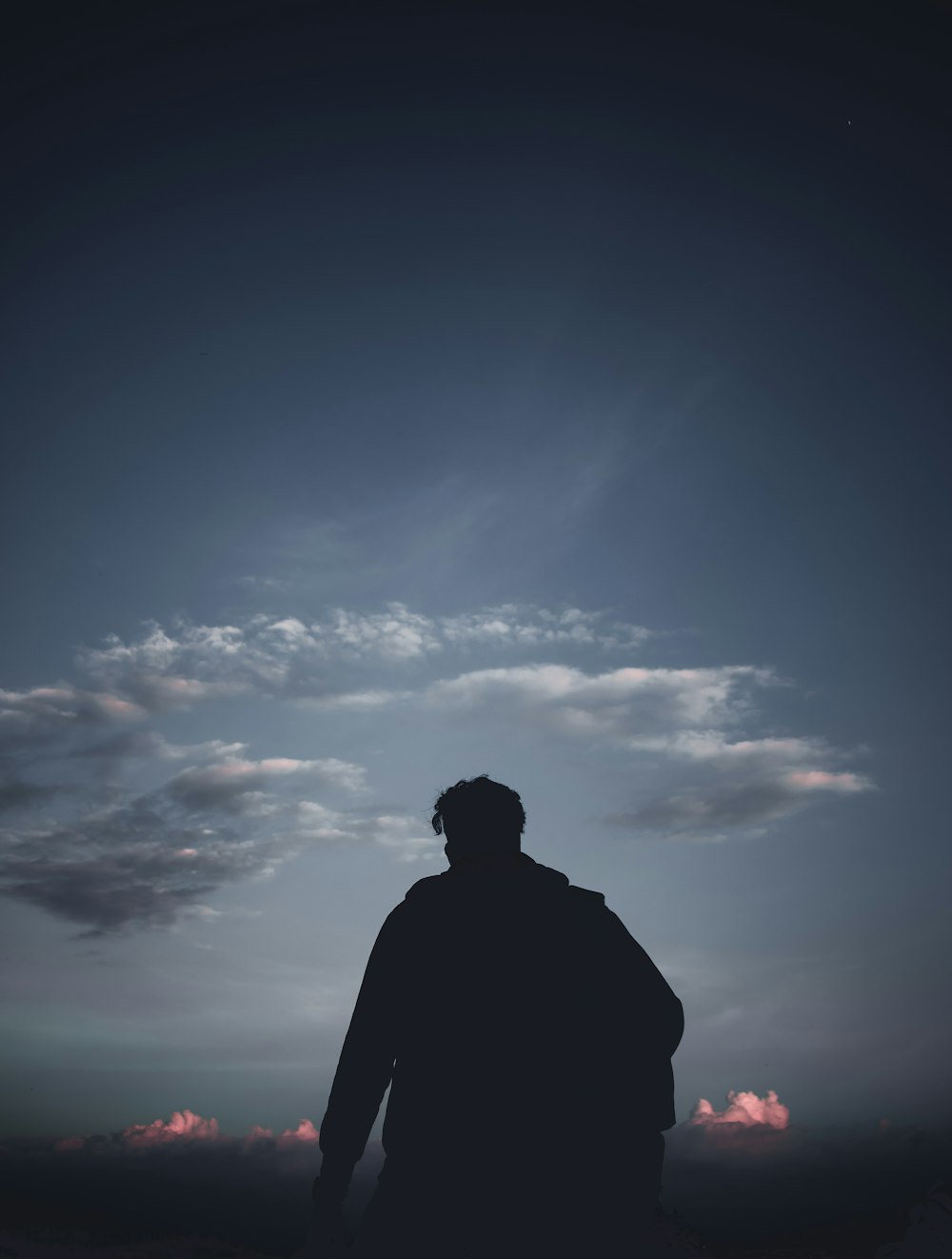 a man standing in front of a cloudy sky