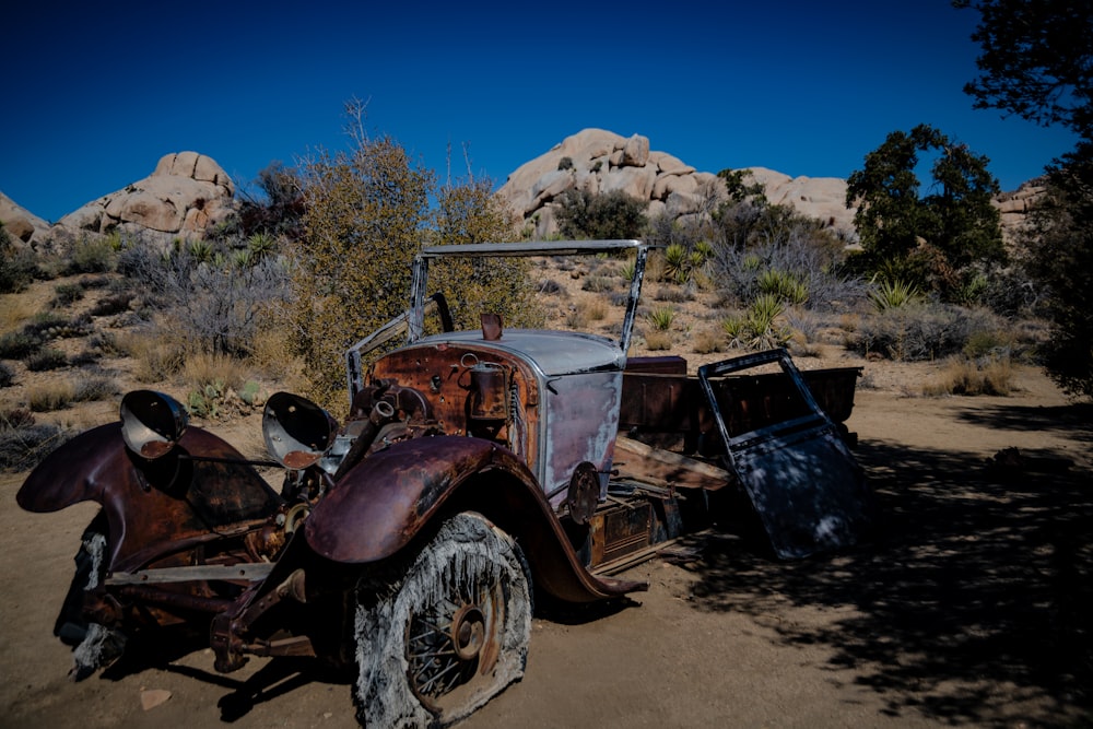 an old rusted out car in the desert