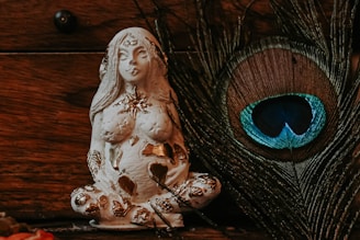 a statue of a woman sitting next to a peacock feather