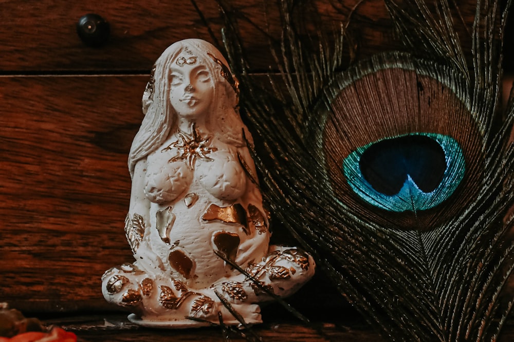 a statue of a woman sitting next to a peacock feather