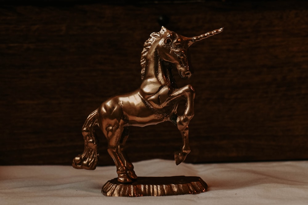 Une statue dorée d’une licorne sur un drap blanc