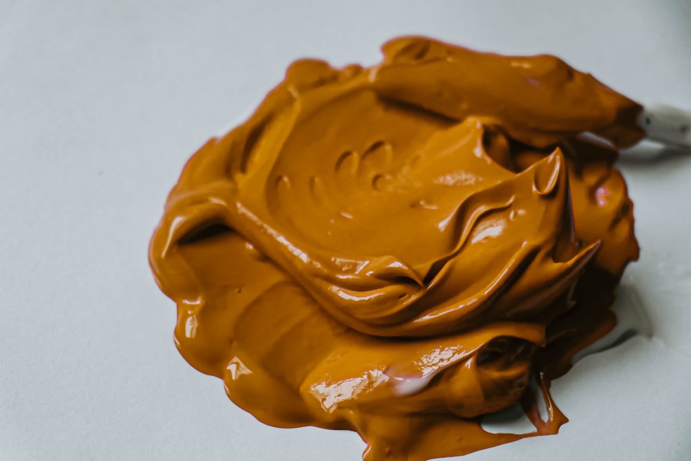 a close up of a chocolate frosting on a white surface