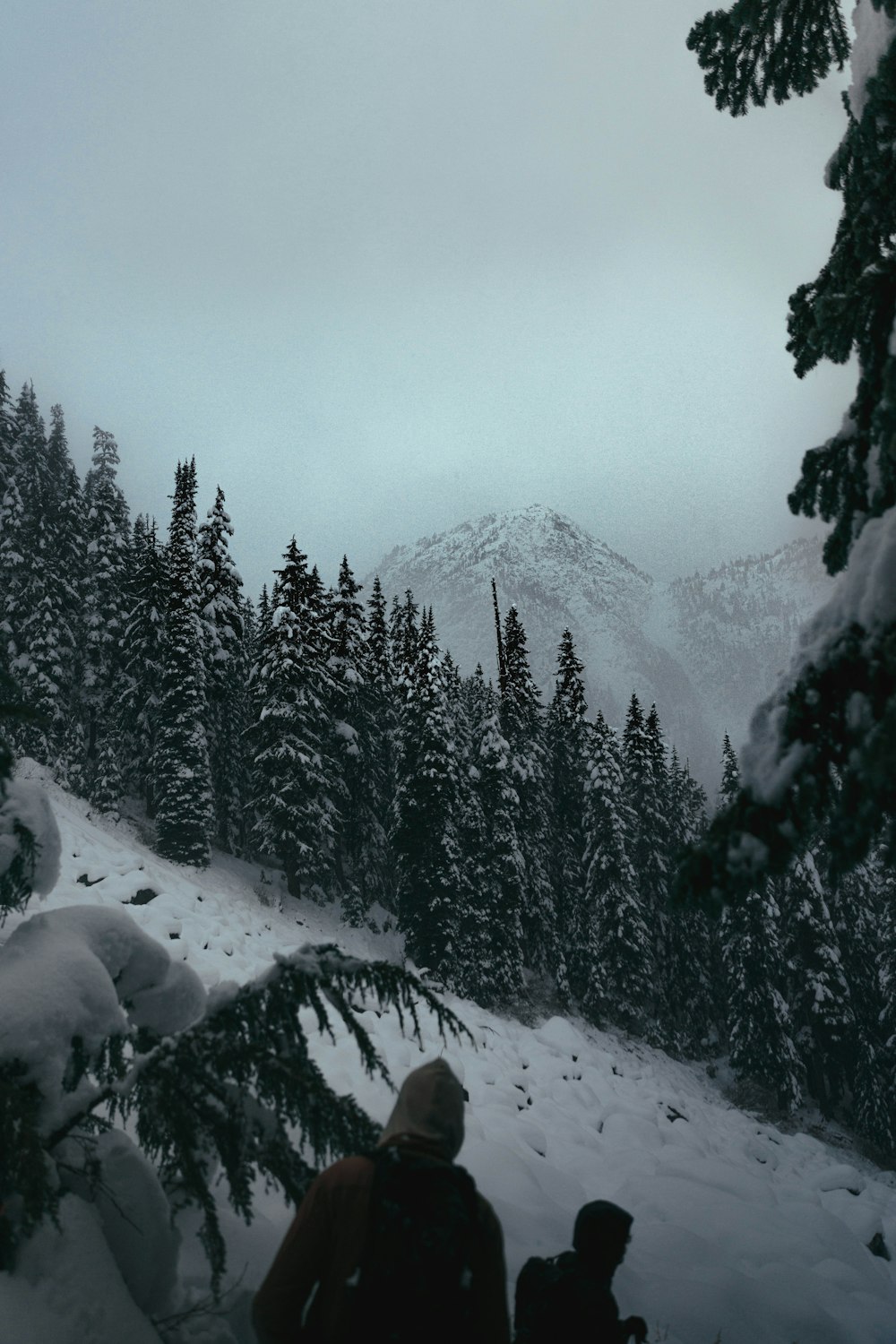 a couple of people standing on top of a snow covered slope