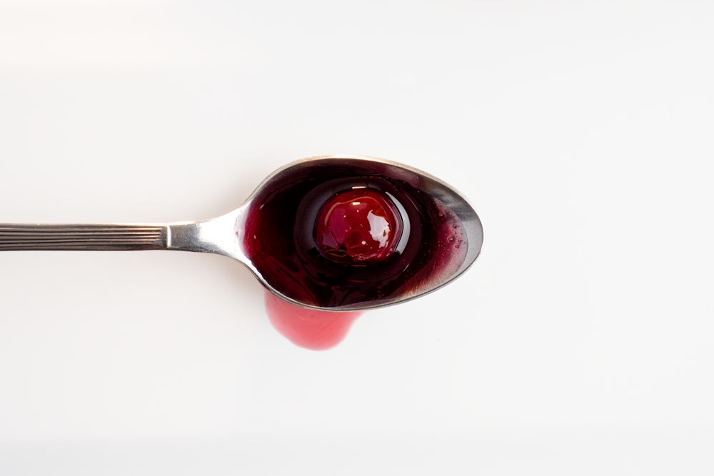 a spoon with a red liquid inside of it