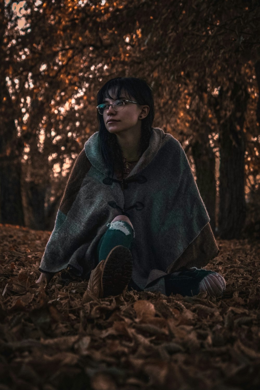 a woman sitting on the ground covered in leaves