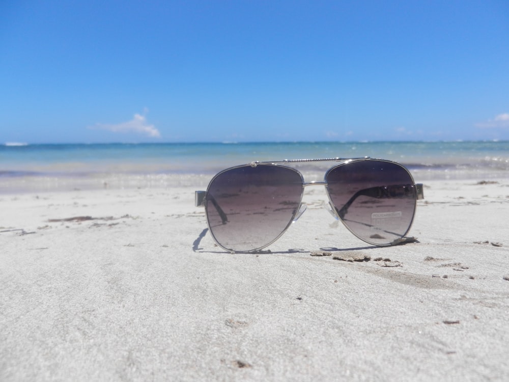 a pair of sunglasses sitting on top of a sandy beach