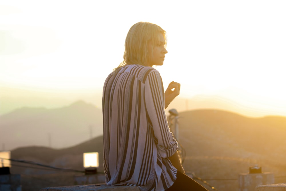 a woman sitting on top of a stone wall