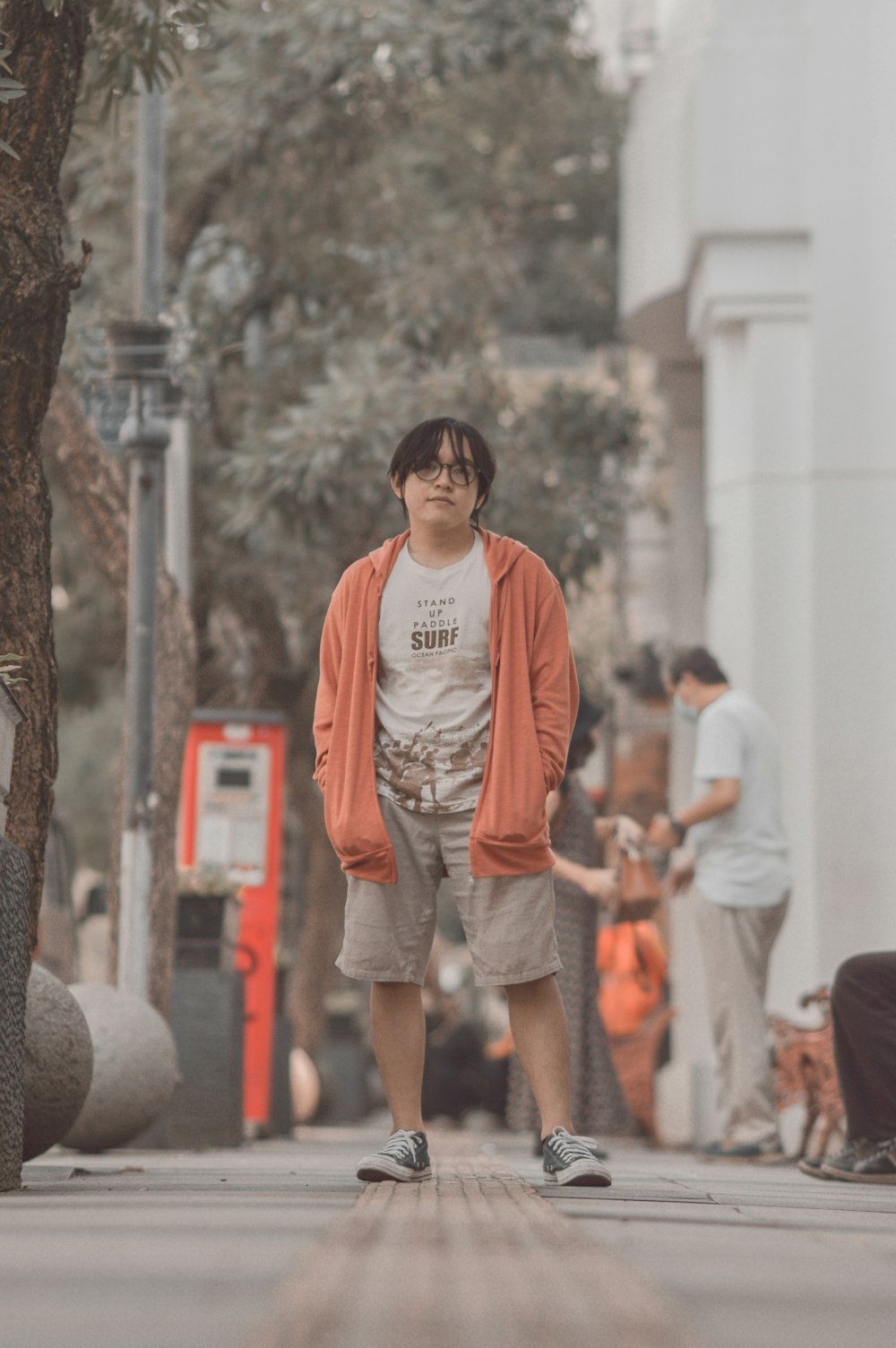 a man standing on a sidewalk next to a tree