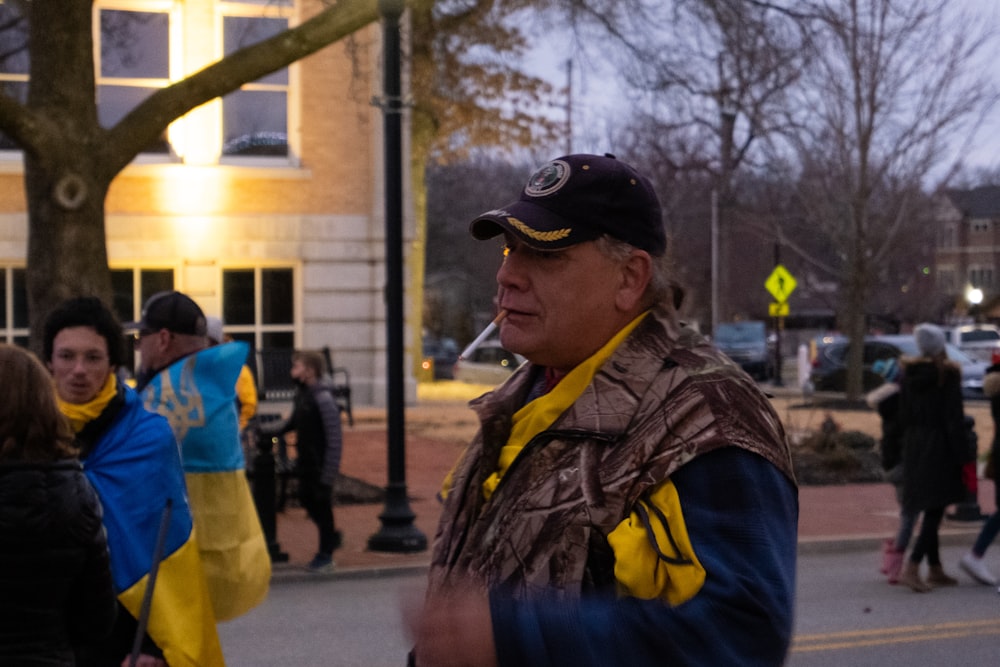 a man in a hat and scarf standing in the street