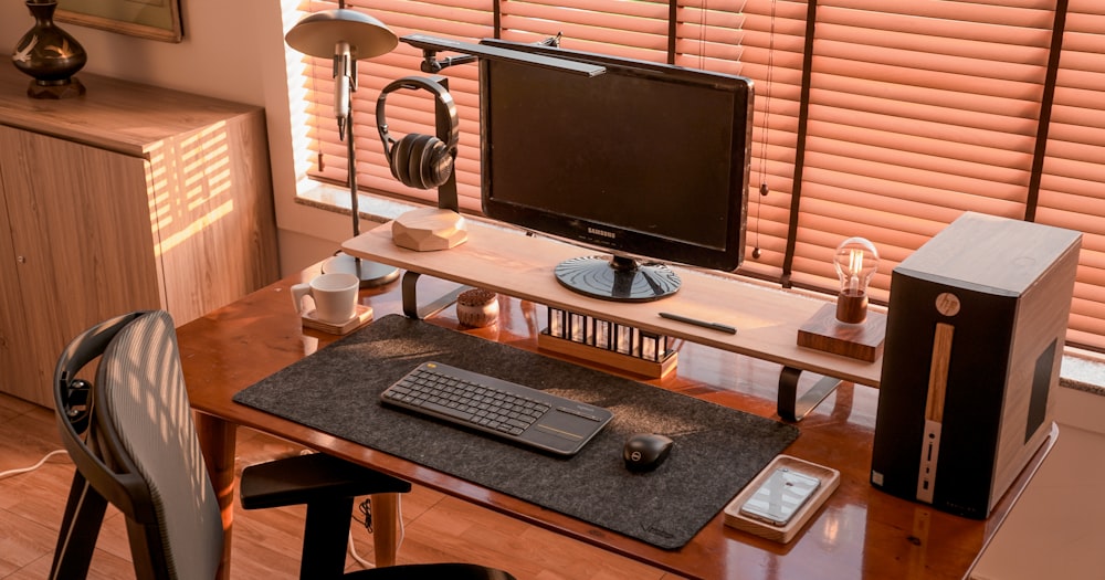 a computer desk with a monitor, keyboard and headphones