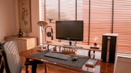 a computer desk with a monitor, keyboard and speakers
