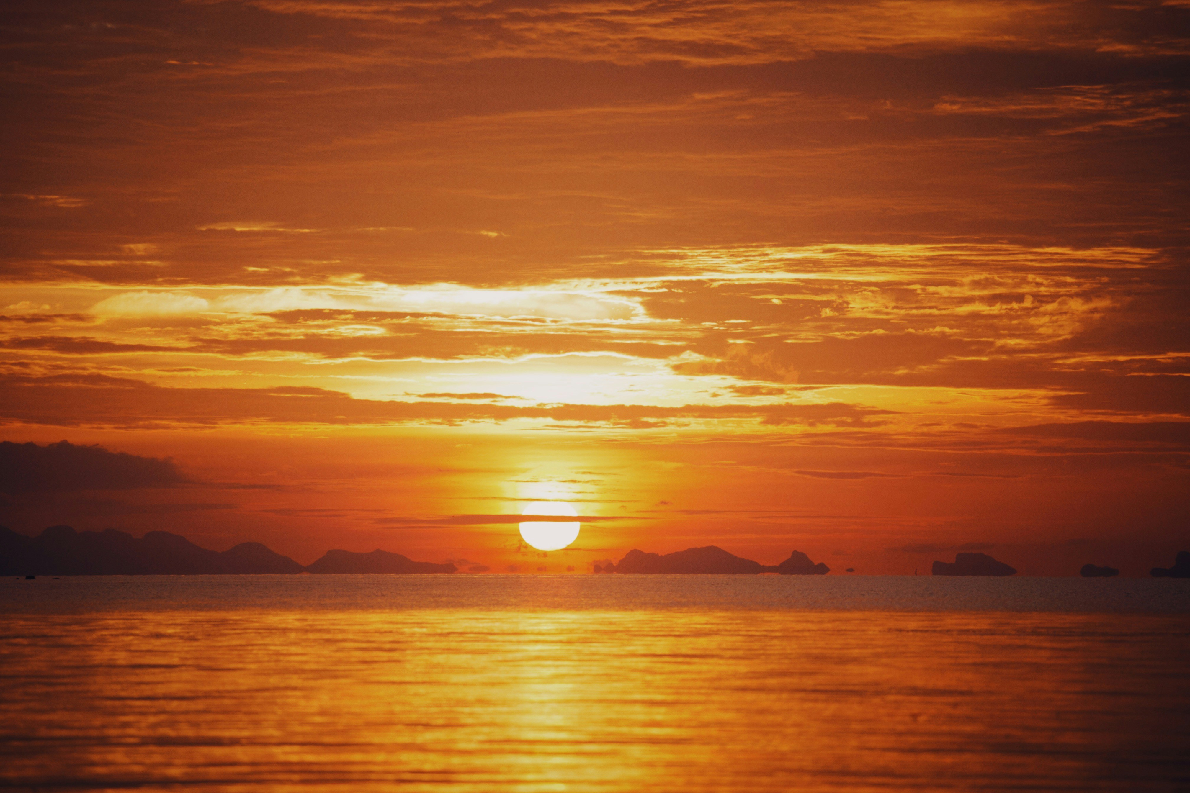 a sunset over a body of water with mountains in the background