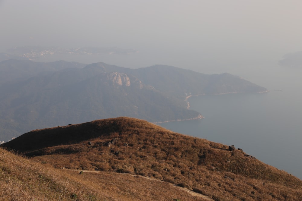 a grassy hill with a body of water in the distance