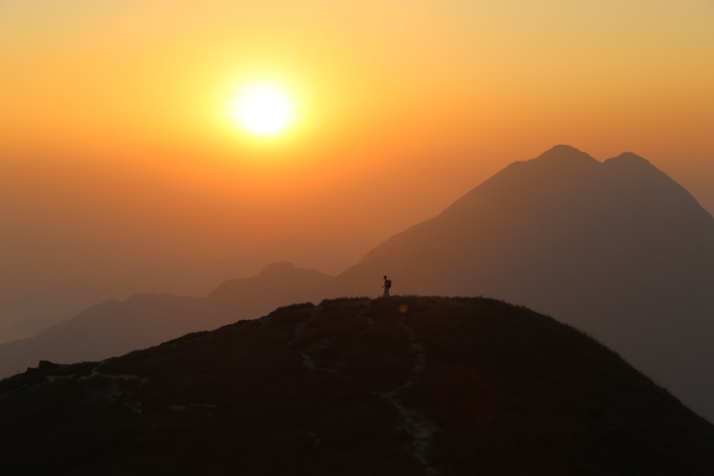 a person standing on top of a mountain at sunset