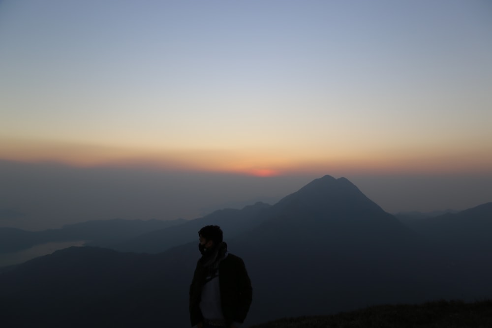 a man standing on top of a mountain at sunset