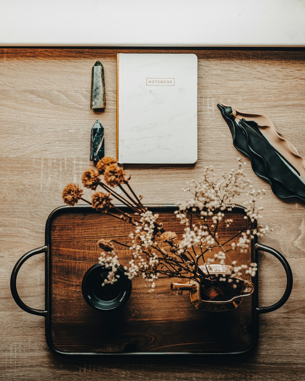 a wooden table topped with flowers and a notebook
