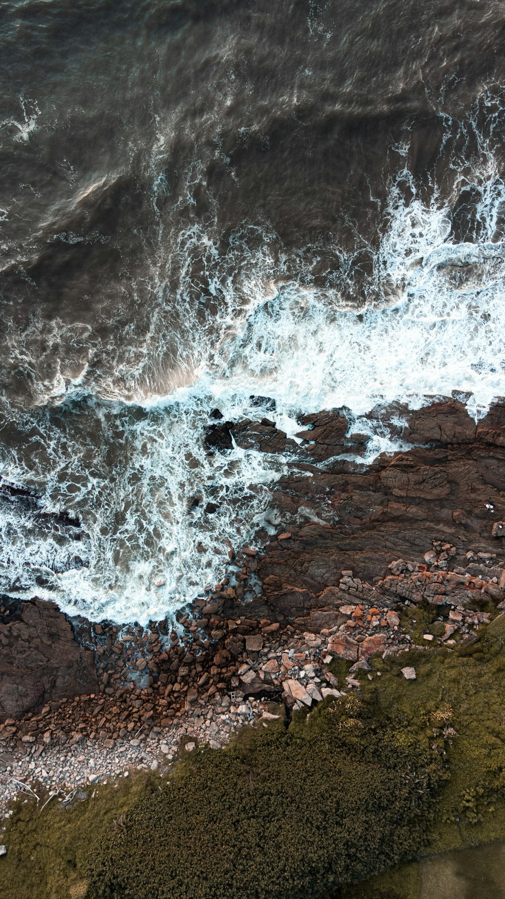 an aerial view of the ocean and rocks