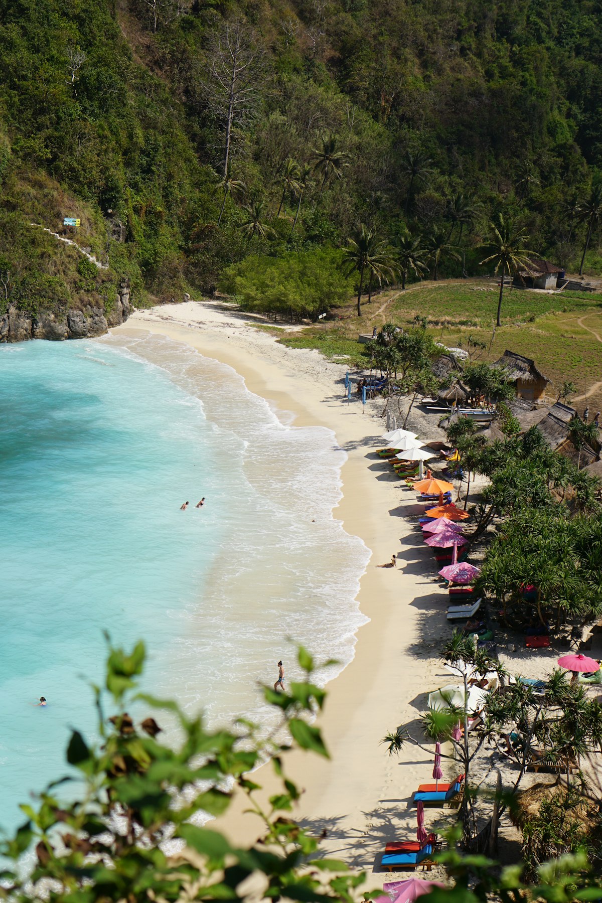 Nusa Penida December — beach with colourful umbrellas during holiday season monsoon