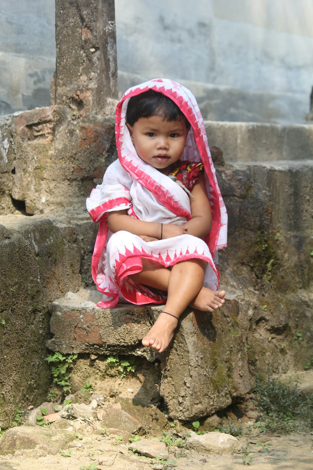 a little girl sitting on top of a rock