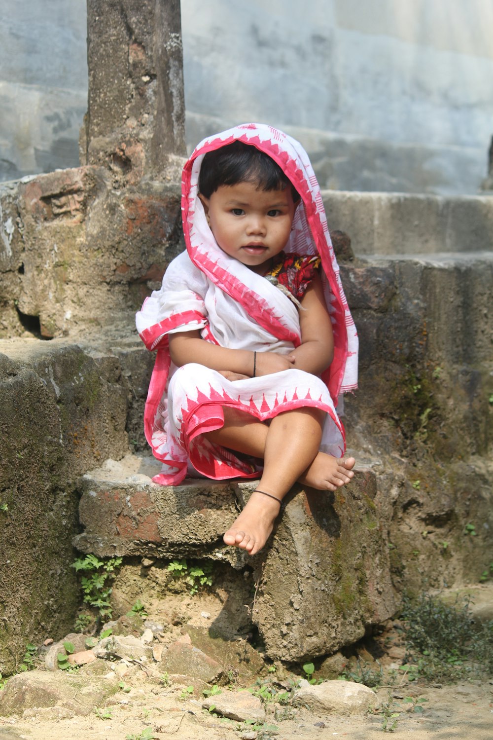 Una bambina che si siede sulla cima di una roccia