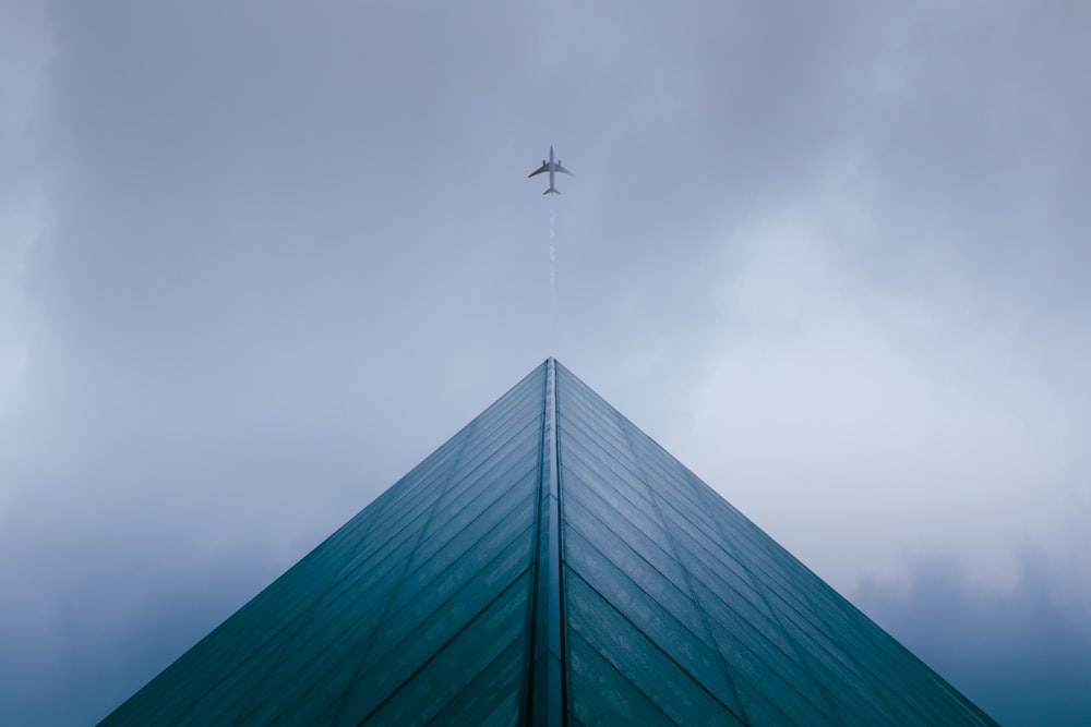 an airplane flying over a tall building on a cloudy day