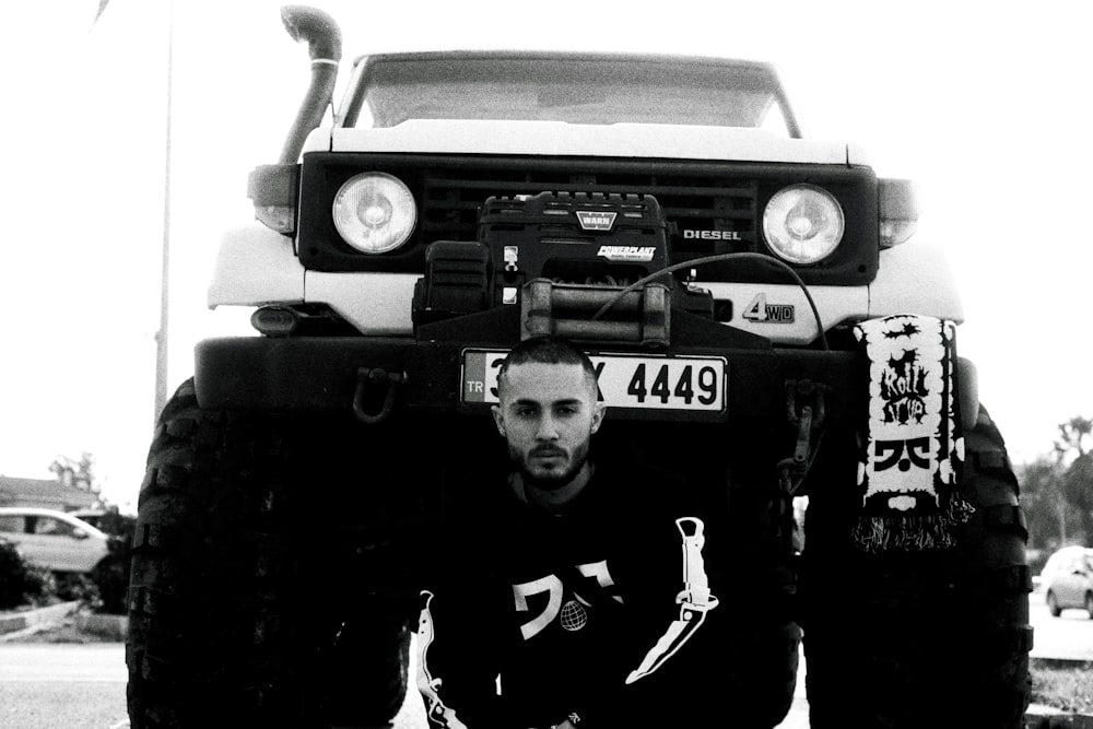 a man kneeling in front of a large truck