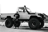 A smiling customer receiving mobile auto care service beside their desert vehicle.