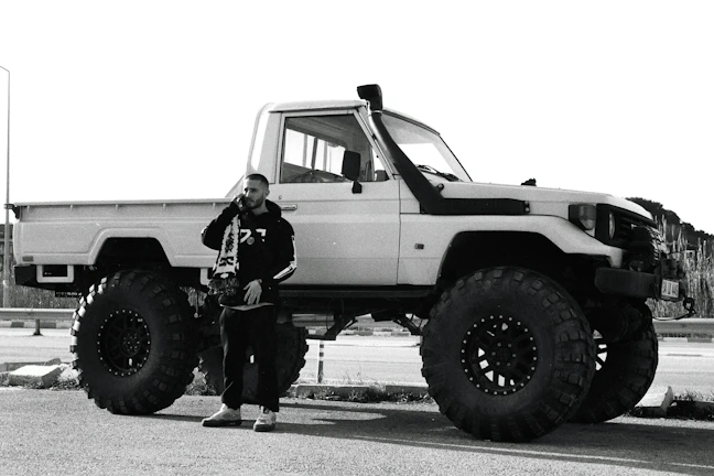 A smiling customer receiving mobile auto care service beside their desert vehicle.