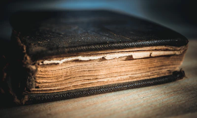 Close-up of a worn leather-bound book with yellowed pages open on a wooden table