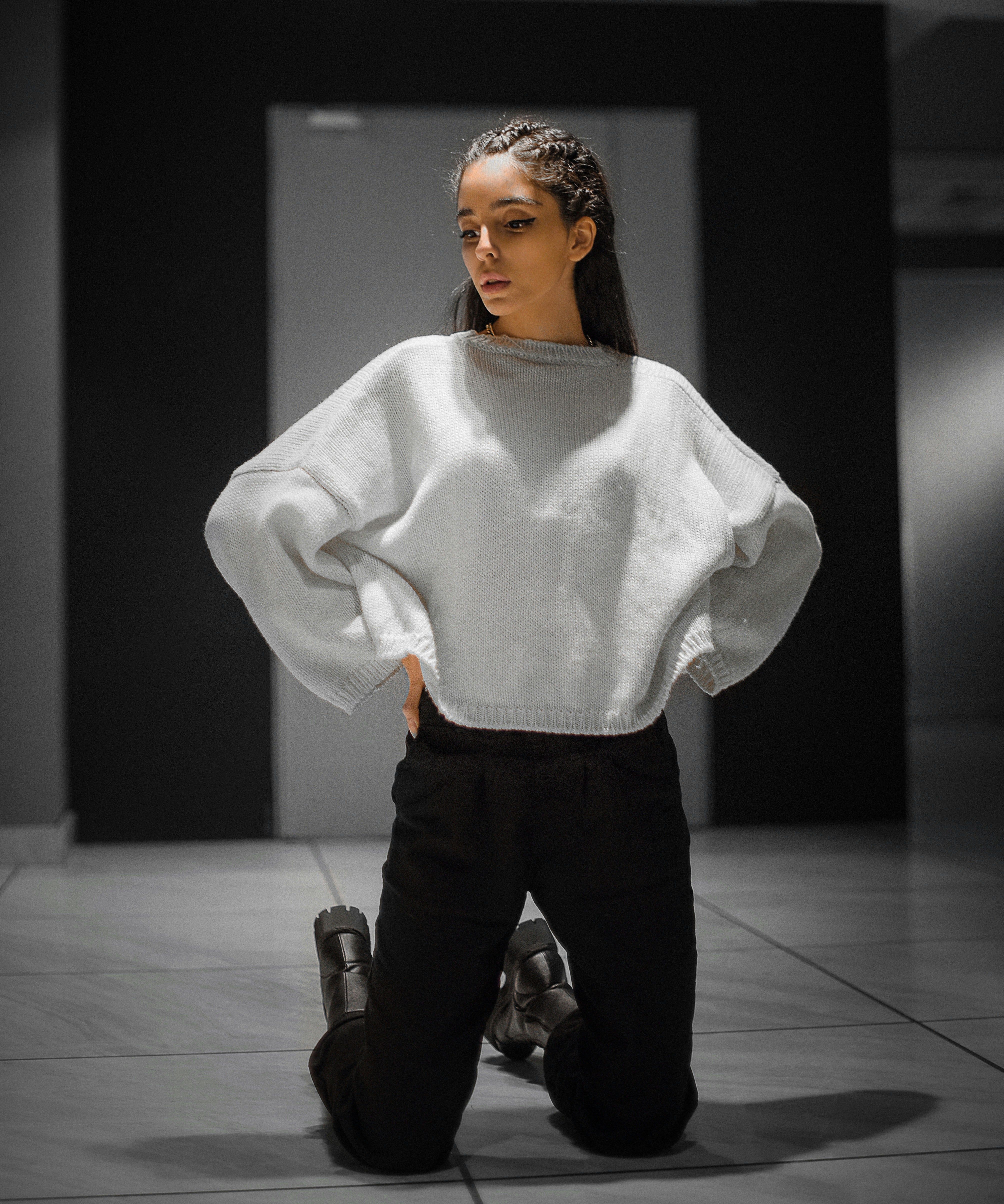 a woman in a white sweater and black pants