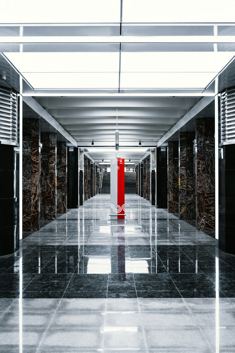 a long hallway with a red pillar in the middle of it