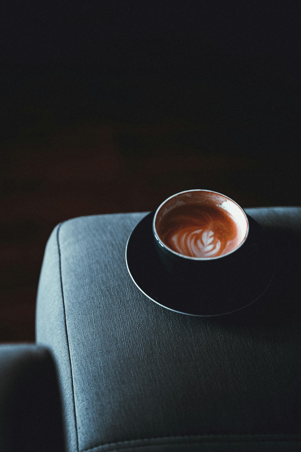 a cup of coffee sitting on top of a black chair