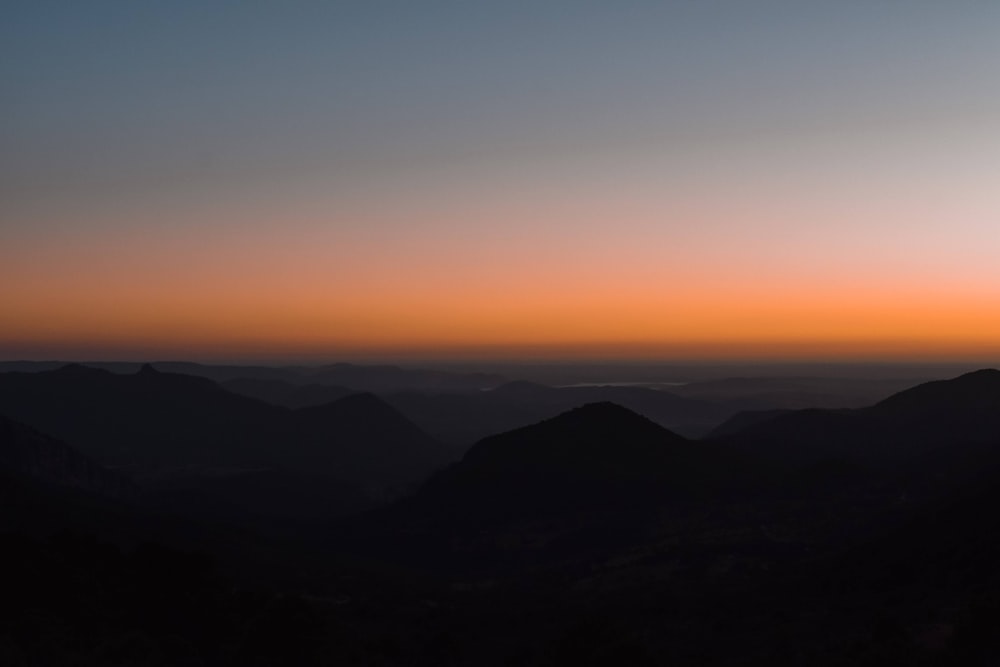 the sun is setting over a mountain range