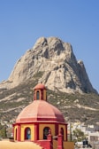 a red and yellow building with a mountain in the background