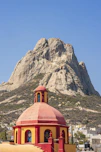 a red and yellow building with a mountain in the background