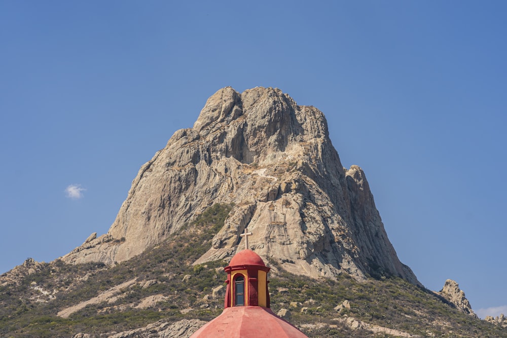 a red dome on top of a building in front of a mountain